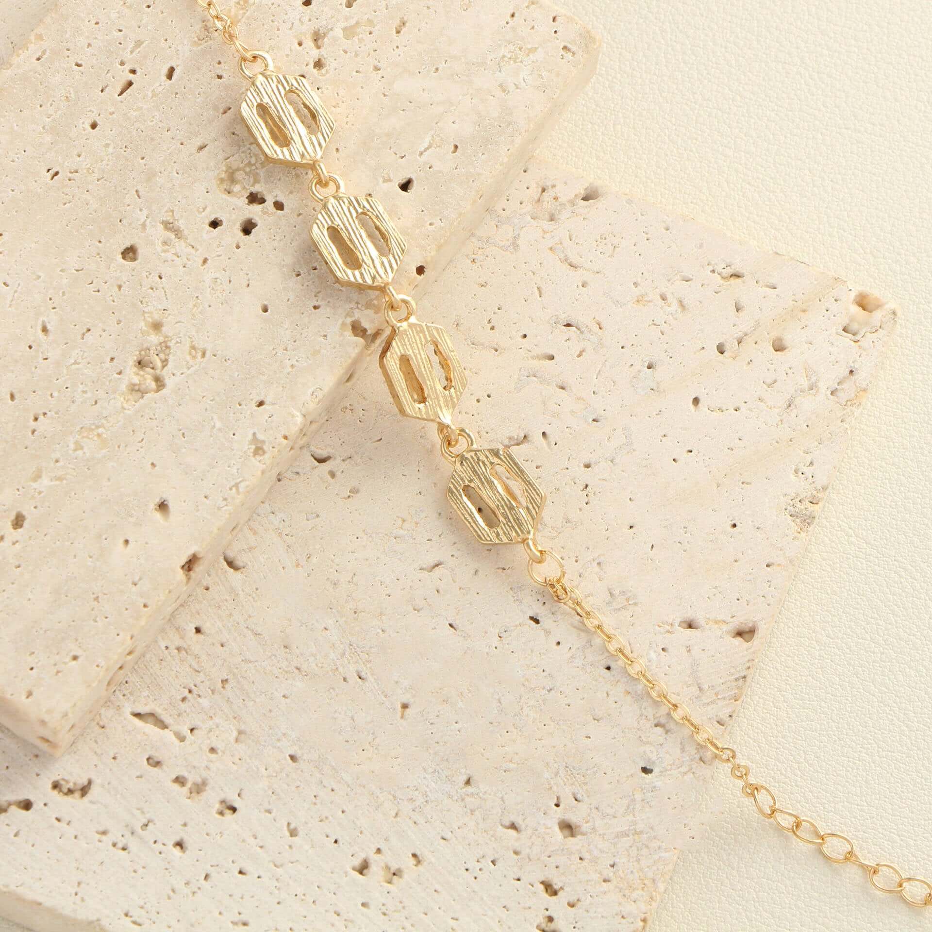 Rhinestone geometric anklet set featuring gold layered design on textured surface.