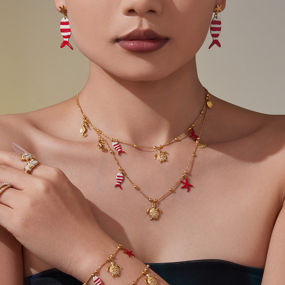 Gold plated ocean charm jewelry set featuring whimsical fish and sea life designs on necklace and earrings.