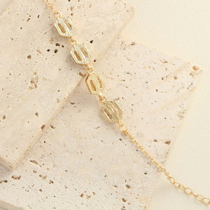 Rhinestone geometric anklet set featuring gold layered design on textured surface.